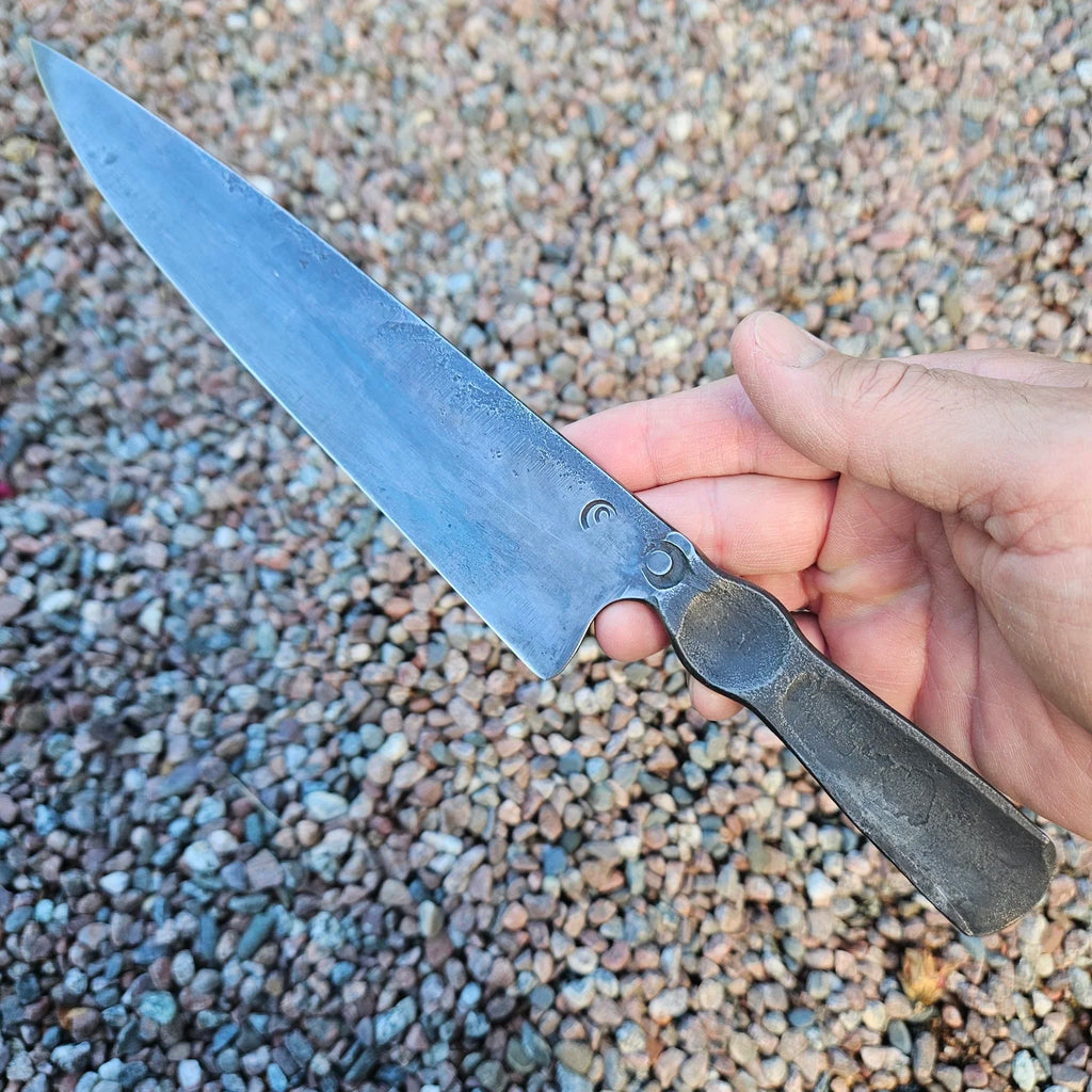 Robust kockkniv 'Mr Dark steel' i ett stycke Apex Ultra kolstål med mörk 'brute de forge' finish. Vänster sida, vinkel